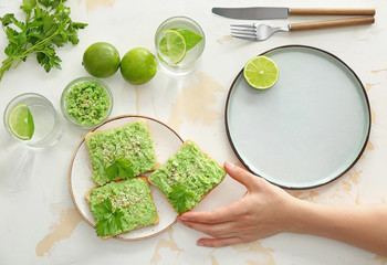 Woman eating tasty avocado toasts at table
