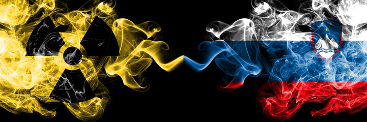 Slovenia, Slovenian vs nuclear smoky mystic flags placed side by side. Thick colored silky smokes combination of Slovenia, Slovenian flag and radioactive sign.