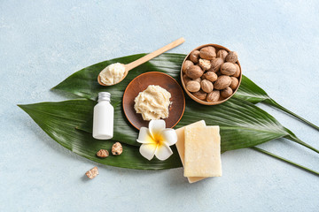 Shea butter with soap and cream on color background