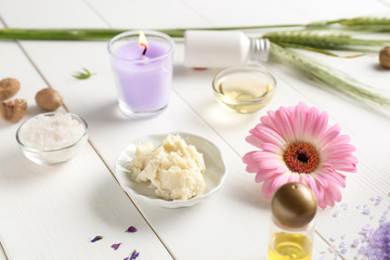 Obraz na płótnie Canvas Shea butter with cosmetic products and candle on white wooden background