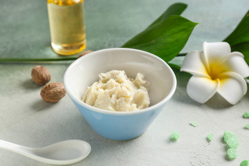 Bowl with shea butter on light background