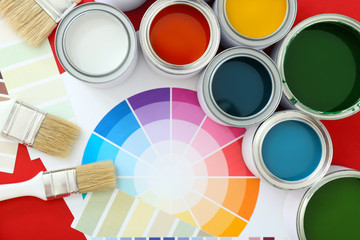 Cans of paints with brushes and palette samples on color background