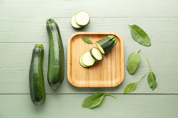 Fresh zucchini squashes with plate on wooden background