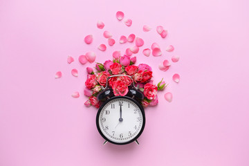 Beautiful fresh flowers and clock on color background