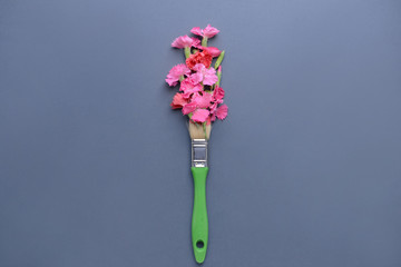 Beautiful fresh flowers and paint brush on color background