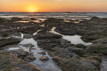 Sunset over the ocean with breaking waves