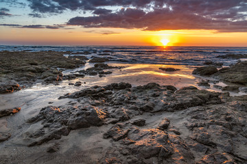 Vivid sunset over the ocean with reflections on the beach