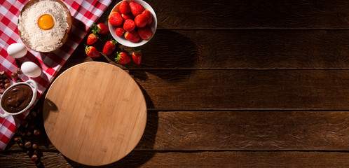 Strawberry and  hazelnut cream at wooden rustic background with copyspace on round pizza desk. Set of fresh fruit and hazelnut. Pizza ingredients. Brazilian sweet pizza concept, top view.