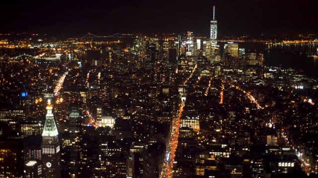 Aerial view of tall skyscapers in Manhattan lit up at night.
