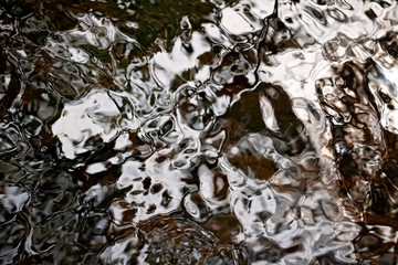 Brown, Black and White Ripples on a River Detail. Abstract background. Water closeup. Wet pattern. Beautiful and unique. Peaceful nature.