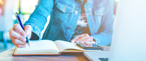 Woman hand writing on notepad with a pen.