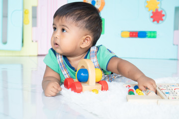 ittle baby boy lying and play wooden toy