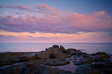 Beautiful pink sunset clouds over the rocky beach