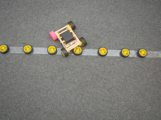 Homemade model driven car from wooden sticks. The road is made of gray nap. Wheels.