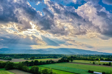 Fototapeta na wymiar Dramatic clouds above rural landscape, sun rays through clouds
