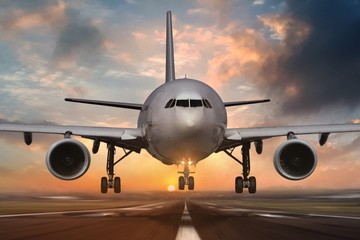 Fototapeta na wymiar Airplane landing on airport runways during sunset