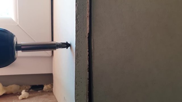 Handheld shot of screwing a plaster board panel to a wall in the house which is under construction