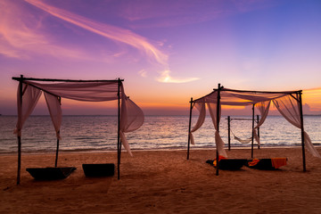 Fototapeta premium The white beach tents and beach chairs on beautiful beach at sunset time twilight sky background.
