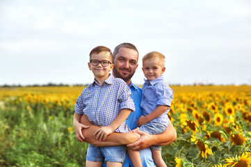 Fototapeta premium Young father with his sons on a walk . A parent holds two sons in his arms . Father's day. Happy father