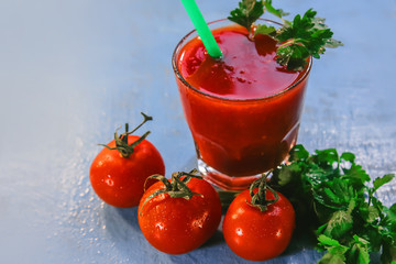 tomato juice in a glass, fruits of tomato and parsley.