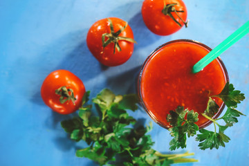 tomato juice in a glass, fruits of tomato and parsley.