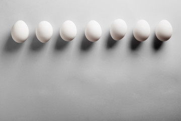 White eggs deep shadows on gray background. Top view, copy space