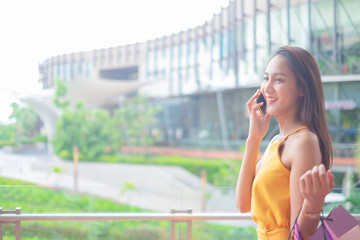 Beautiful women with shopping bags and smartphone enjoying in shopping standing outdoors of shopping mall, shopping concept