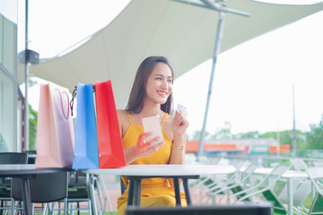 Beautiful women with shopping bags and smartphone enjoying in shopping standing outdoors of shopping mall, shopping concept