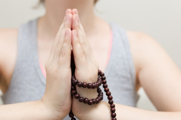 A closeup of a woman in yoga pose, holding buddhist beads in hands