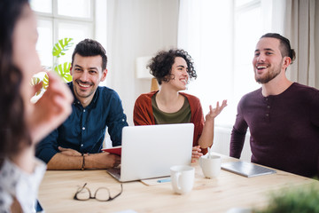 A group of young friends with laptop indoors, house sharing concept.