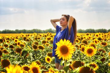 Young happy girl on a walk in a field with sunflowers