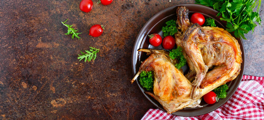 Whole baked rabbit with greens and tomatoes on a plate. Tasty dietary meat. Top view, flat lay. Banner