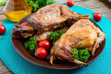 Whole baked rabbit with greens and tomatoes on a plate. Tasty dietary meat.