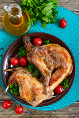 Whole baked rabbit with greens and tomatoes on a plate. Tasty dietary meat.