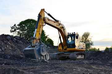 A heavy excavator in a working at granite quarry unloads old concrete stones for crushing and recycling to gravel or cement. Special heavy construction equipment for road construction.