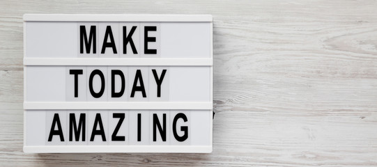 'Make today amazing' words on a lightbox on a white wooden surface. From above, overhead, flat lay, top view. Space for text.