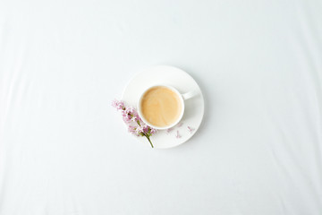 Morning breakfast with coffee cup and lilac branches on white background. Flat lay, top view women background. Minimal concept, wedding, valentine day