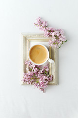 Obraz na płótnie Canvas Cup of coffee, lilac branch and frame on white background. Flat lay, top view, copy space, wedding, female morning breakfast, woman day concept