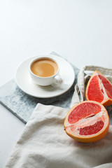Flat lay coffee with eco craft tissue bag and grapefruit on marble plate and white background. Minimal hipster concept, office desk, minimalism