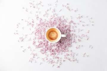 Morning breakfast with empty coffee cup, lilac flowers on white background. Flat lay, top view women background. Minimal concept, wedding, valentine day