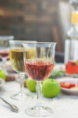 Glasses of white and rose wine, grilled fish plates, vegetables, salad and fruits on the table. Summer party in the backyard. Vertical shot