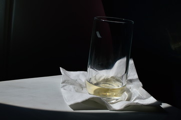 a glass of champagne with a ray of sun caught from the porthole on board in an airplane on a...