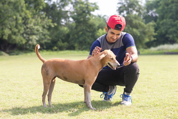 Young Indian sports man playing with dog in sports ground while jogging. Male  Sports and fitness concept.