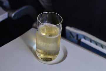 a glass of champagne with a ray of sun caught from the porthole on board in an airplane on a...