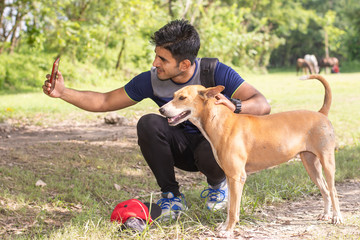 Young Indian sports man playing with dog in sports ground while jogging. Male  Sports and fitness concept.