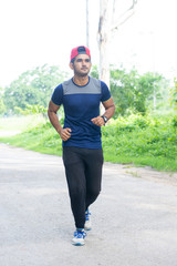 Athletic young man running in the sports ground. Healthy lifestyle , fitness and sports concept.