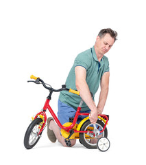 Obraz premium Man in shorts and a t-shirt is repairing a children's bicycle, in the hands of a wrench. Isolated on white background.