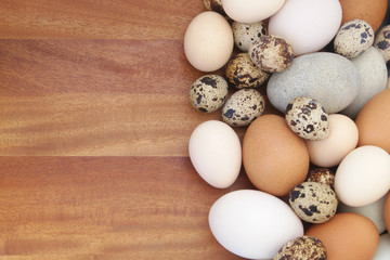 Different eggs on wooden background,  quail, chicken and duck eggs