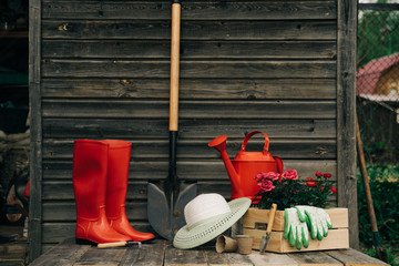 Shovel, watering can, hat, rubber boots, box of flowers, gloves and garden tools