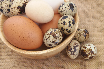Many different eggs on jute background. Quail, chicken and duck eggs on rustic burlap sack